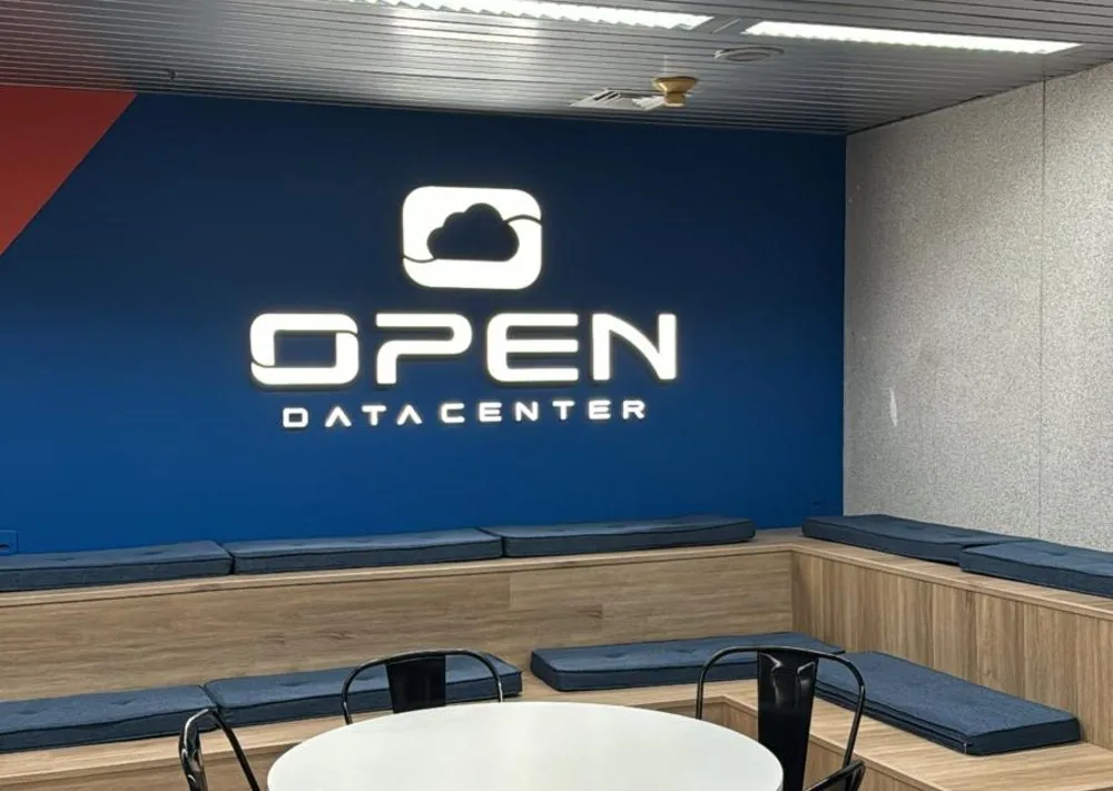 Área de convivência do escritório da OPEN Datacenter, com a marca na parede
